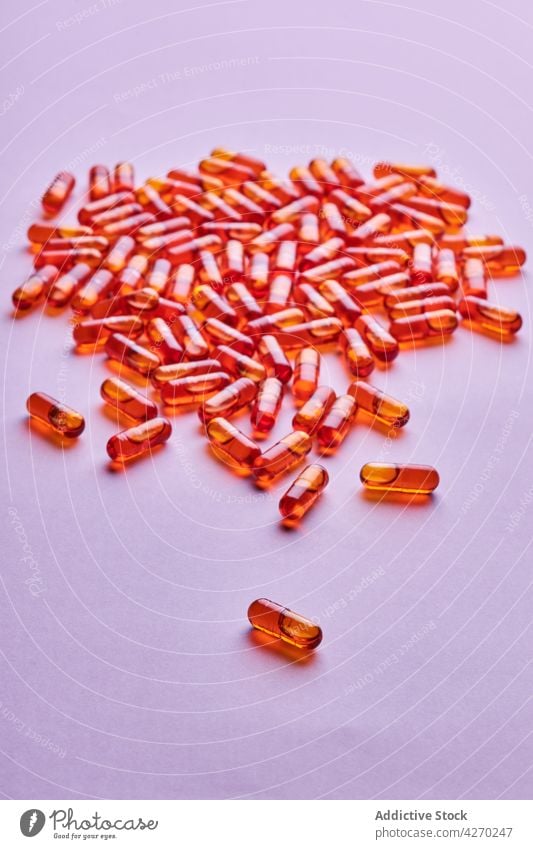 Orange pills scattered on pink surface drug medication capsule cure composition orange remedy vitamin treat pharmacy health care concept colorful pharmaceutical