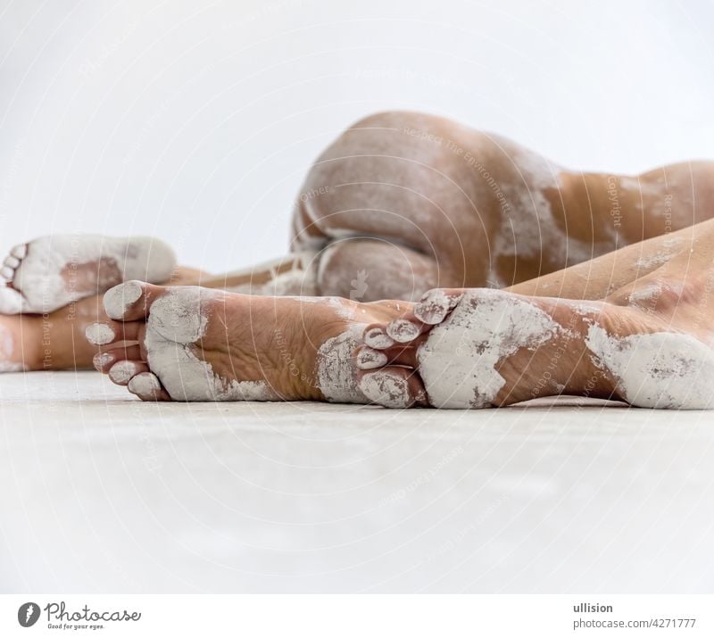 three feet of two young abstract painted sexy women in white paint lying on the artists studio floor, copy space girls attractive tiptoe sisters naked concept