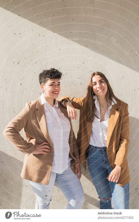 Happy girlfriends standing near wall women smile street trendy confident sunny happy female young together friendship jacket jeans positive elegant lifestyle