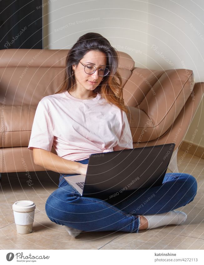 Young women using laptop while sitting on the floor at home wear mockup t-shirt learn student Lifestyle jeans glasses serious concentrated indoor sofa couch