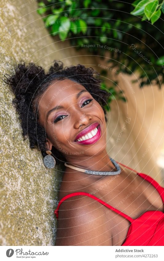 Charming black woman leaning on stone formation confident posture cool style charm wall charming charismatic feminine female gaze personality bare shoulders