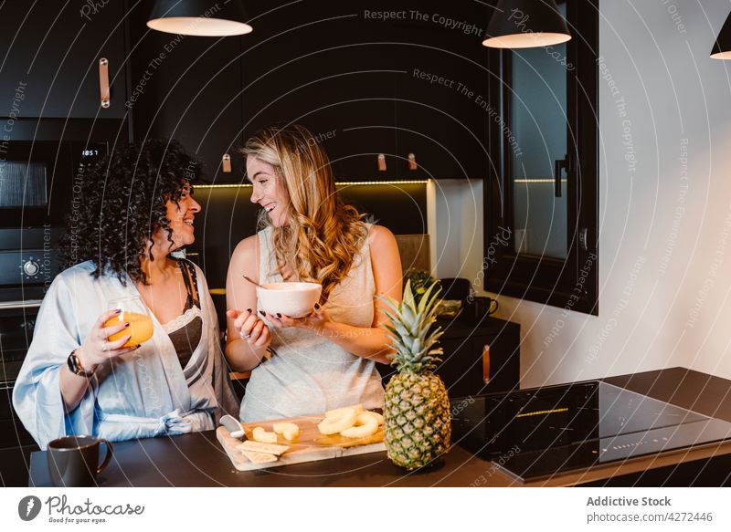 Happy girlfriends having fun in morning in kitchen women couple laugh cut pineapple joy breakfast lgbt cereal female pleasure lesbian cheerful happy berry