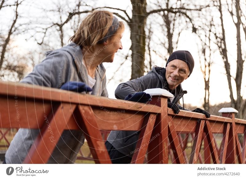 Aged couple doing push ups while leaning on fence exercise action positive activity together old training leisure man woman active sport aged senior autumn park