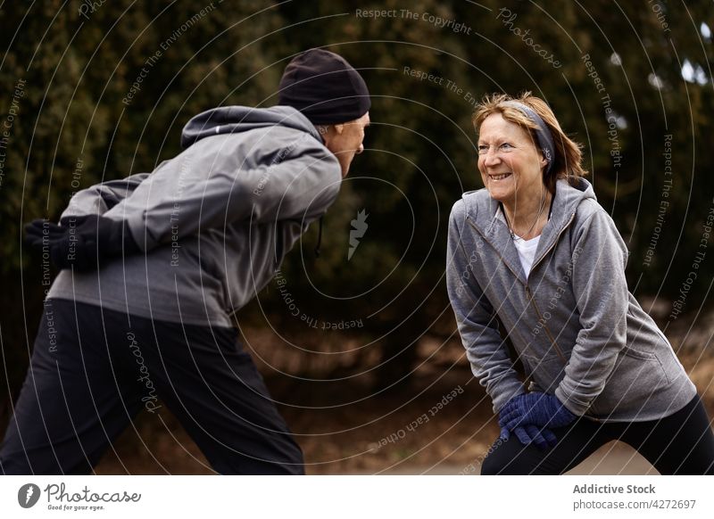 Smiling senior couple spreading legs during training sport exercise outstretch enjoy active activity man woman together aged old positive park energy sportswear