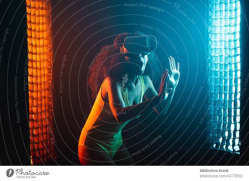 Unrecognizable amazed black woman experiencing virtual reality in goggles vr neon entertain immerse technology astonish mouth opened using gadget device explore