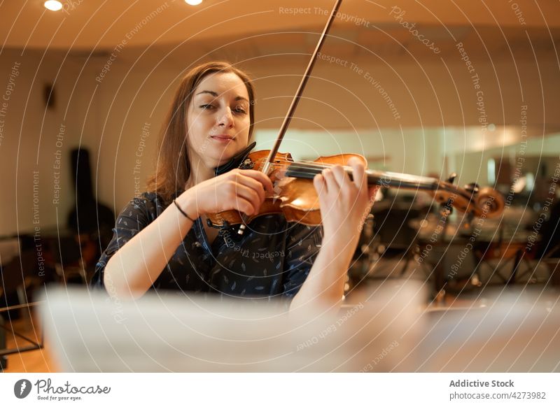 Female violinist performing classical music in hall woman musician play rehearsal instrument skill melody sound talent studio acoustic audio tune artist