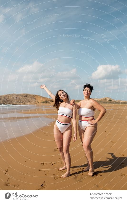 Happy friends standing in foamy sea women wave girlfriend fun beach cheerful smile female trip bikini happy summer sunny friendship best friend relationship