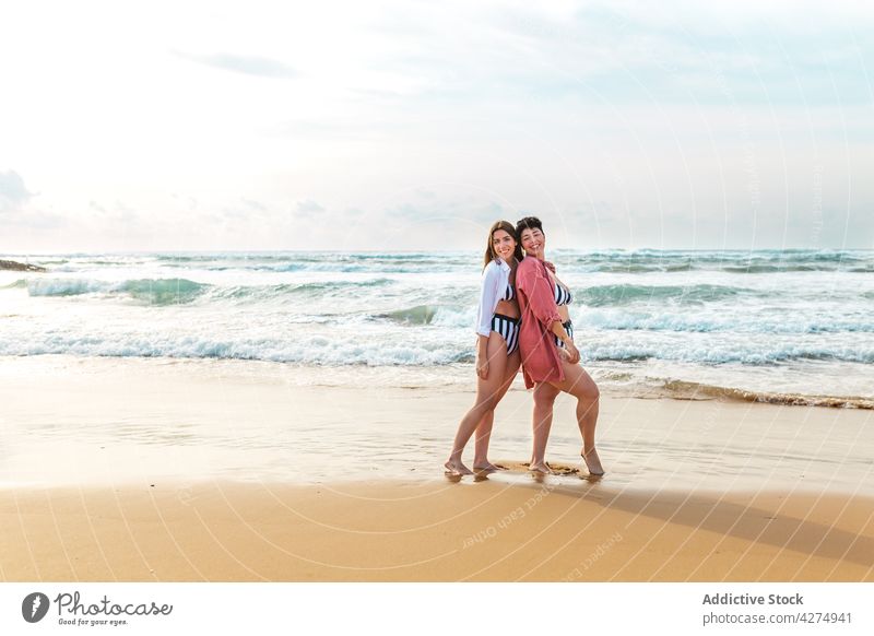 Happy friends standing in foamy sea women wave girlfriend embrace fun cheerful beach smile female trip happy summer sunny friendship best friend relationship