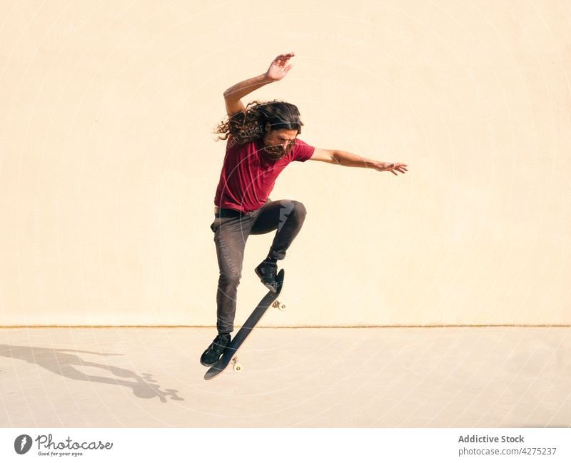 Active skater jumping with skateboard on beige background skateboarder trick sport active balance energy dynamic man fast outstretch walkway motion speed rapid