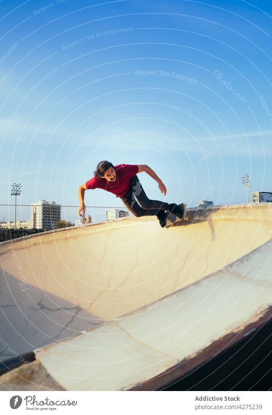 Skater riding skateboard on ramp in city skater ride sport extreme balance talent man skate park skateboarder active energy blue sky cloudy motion speed rapid