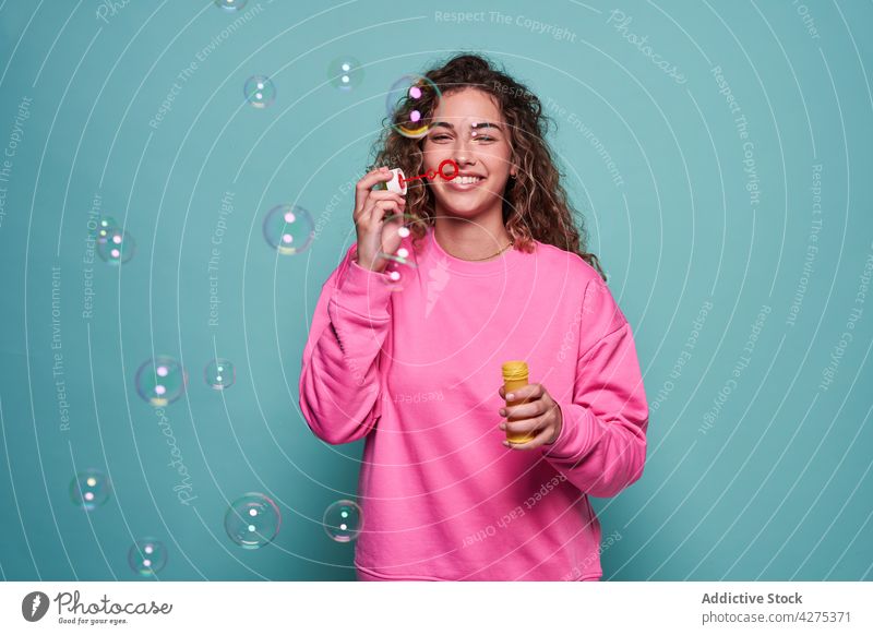 Delighted woman blowing bubbles in studio soap bubble fun laugh pleasure teen joy playful vivid female teenage cheerful optimist glad studio shot carefree