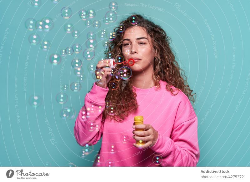 Delighted woman blowing bubbles in studio soap bubble fun laugh pleasure teen joy playful vivid female teenage cheerful optimist glad studio shot carefree