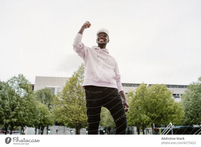 Happy black man with raised arm in park fist up achieve gesture happy glad accomplish win triumph satisfied male hand raised show sign hand up delight victory