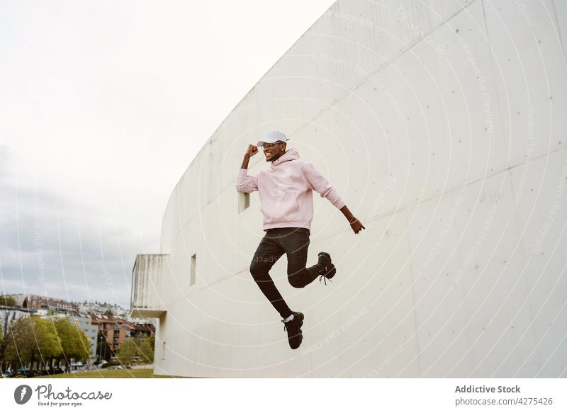 Cheerful black man jumping high above ground laugh motion fun smile happy carefree male positive optimist leap excited joke having fun cheerful african american