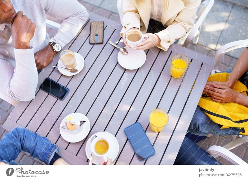 Top view of people drinking some beverages sitting at the table on the terrace of a bar. coffee cafe cup friends tea unrecognizable meeting smartphone lifestyle