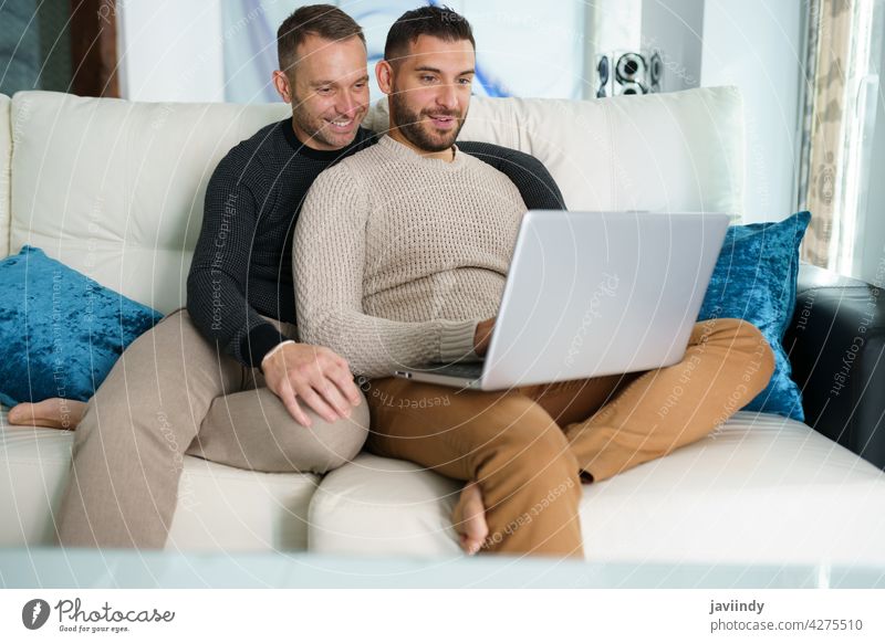 Gay couple consulting their travel plans together with a laptop. gay men homosexual lgbt lgbtq male relationship boyfriend people 30s togetherness man lifestyle