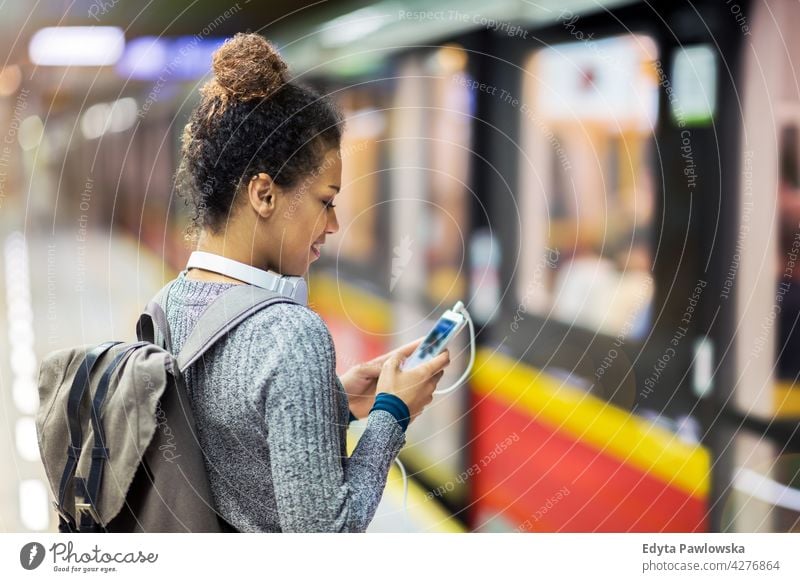 Woman using mobile phone at subway station outdoors day positivity confident carefree people woman young young adult casual beautiful attractive female