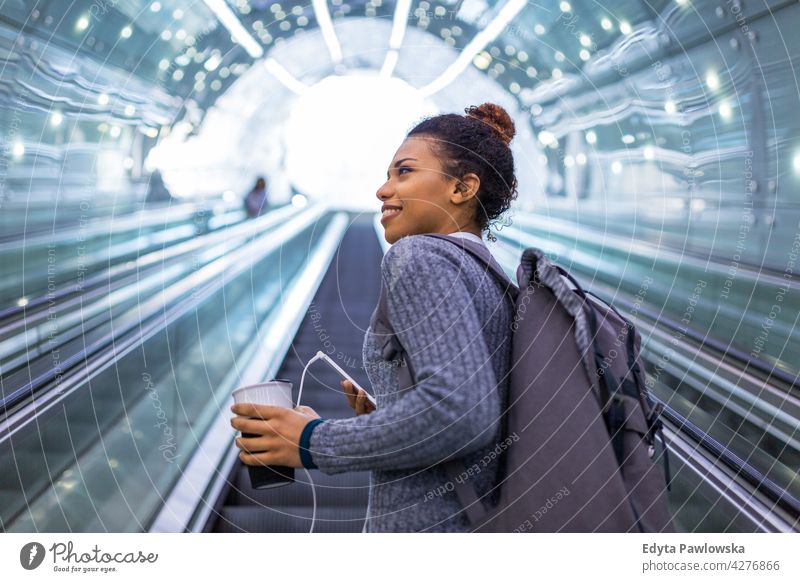 Young woman on escalator using smartphone outdoors day positivity confident carefree people young young adult casual beautiful attractive female one person