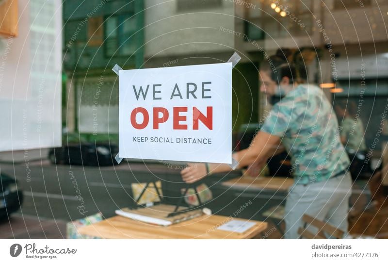 Commercial reopening poster after coronavirus sign cartel we are open keep social distance workers placing tables chairs covid-19 preparing message man