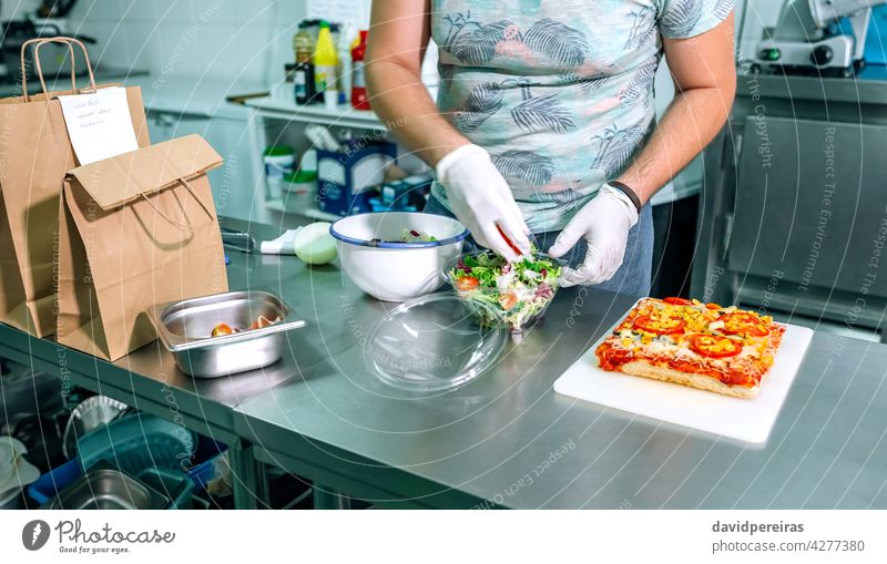 Unrecognizable cook preparing takeaway orders unrecognizable chef preparing orders salad industrial kitchen package gloves hygiene take away