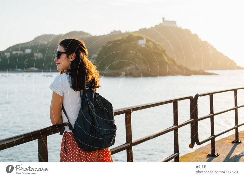 Young tourist woman enjoying the view of San Sebastian bay in Spain at sunset young happy Donostia sea beach La Concha beach island Santa Clara Basque country