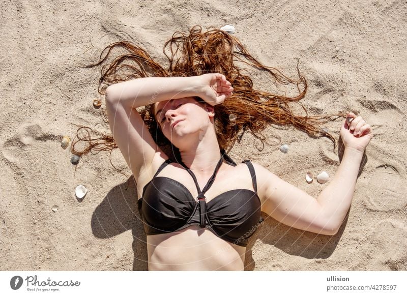 beautiful young woman in black bikini laying in the sunshine on the beach in the sand sexy portrait girl summer hair travel fashion dress beauty body model tan