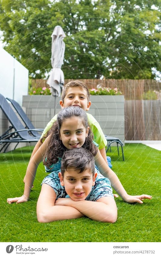 Portrait of three kids lying on a grass background beautiful boy casual caucasian cheerful child childhood children enjoy family field friends friendship fun