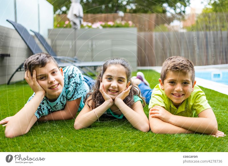 Portrait of three kids lying on a grass background beautiful boy casual caucasian cheerful child childhood children enjoy family field friends friendship fun