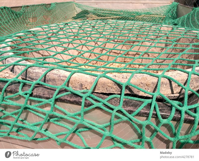 Green safety net over the dirty utensils of a construction company on the flatbed of a truck in Oerlinghausen near Bielefeld in the Teutoburg Forest in East Westphalia-Lippe, Germany