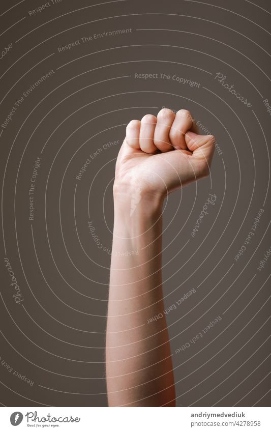 female hand clenched into a fist on a gray background. gesture of fighting, winning or protest. Human hand gesturing sign isolated. Female raised arm presenting popular gesture. copy space