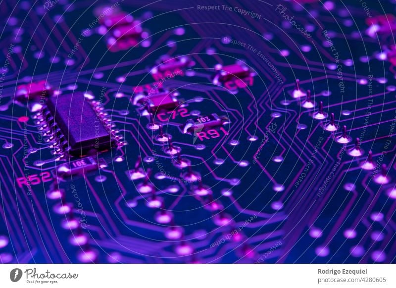 Electronic circuit board components chips resistors illuminated with neon light background blue capacitor card close-up closeup communication computer computing