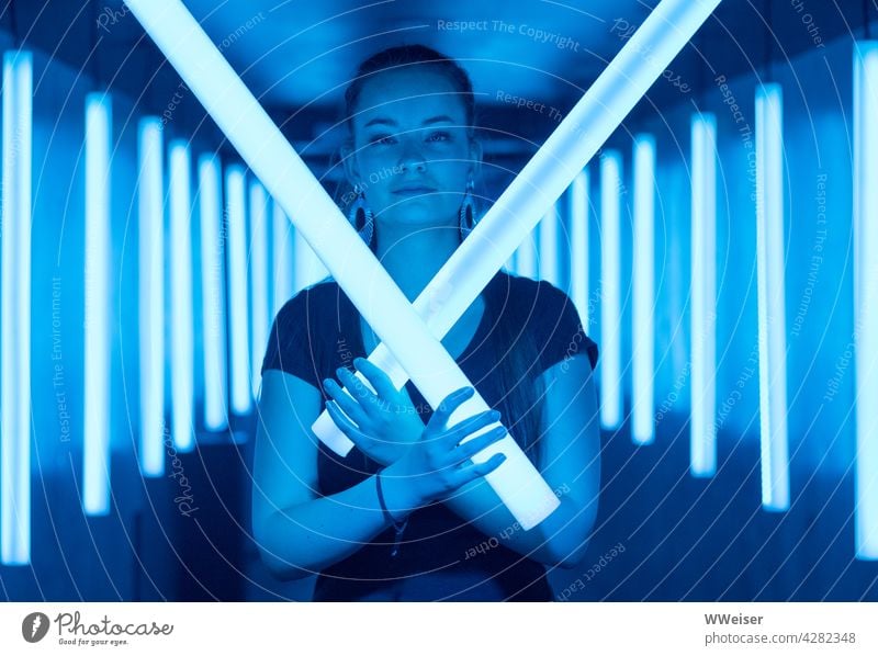 A beautiful young woman knows how to defend herself: May the Force be with her! Light Light tubes Woman Girl Face pretty Young woman Lightsabers Blue