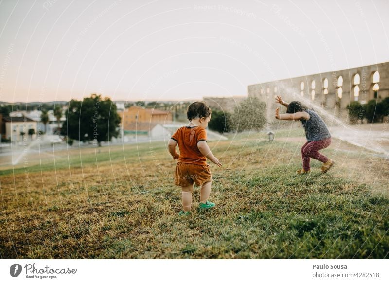 Brother and sister playing with water sprinklers Brothers and sisters Child Water Summer Refreshment Exterior shot Playing Human being Joy Colour photo Infancy