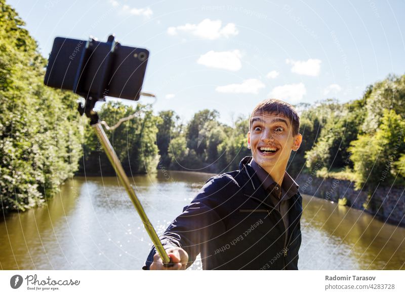 young man making selfie with a selfie stick male camera photo face portrait happy leisure background person make smartphone hand photographer mobile technology