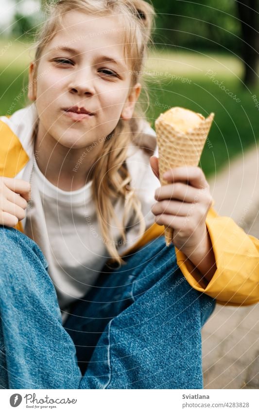 Portrait of a cute blonde teenage girl with ice cream on a walk in the park. Child outdoors summer teenager yellow funny trend happy child kid little dessert