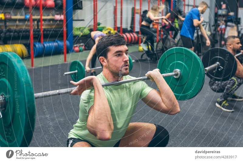 Man practicing weightlifting in the gym sportsman effort dumbbell cross training determination snatch overcoming over head squat self confident strength workout