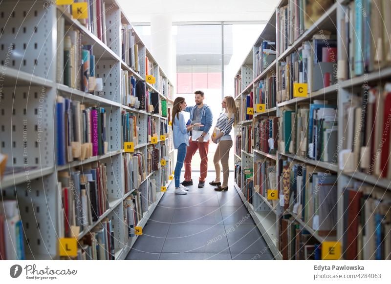 College students in a library enjoying lifestyle young adult people casual caucasian positive happy smiling woman female attractive beautiful bookstore reading