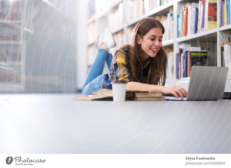 Young female student in a university library enjoying lifestyle young adult people one person casual caucasian positive happy smiling woman attractive beautiful