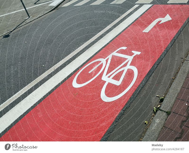 Newly built red bike lane with arrow for right turners on grey asphalt with zebra crossing in the West End of Frankfurt am Main in Hesse, Germany cycle path