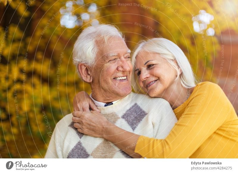 Elderly couple embracing in autumn park family woman love people outdoors portrait together nature two beautiful fall trees yellow senior mature seniors