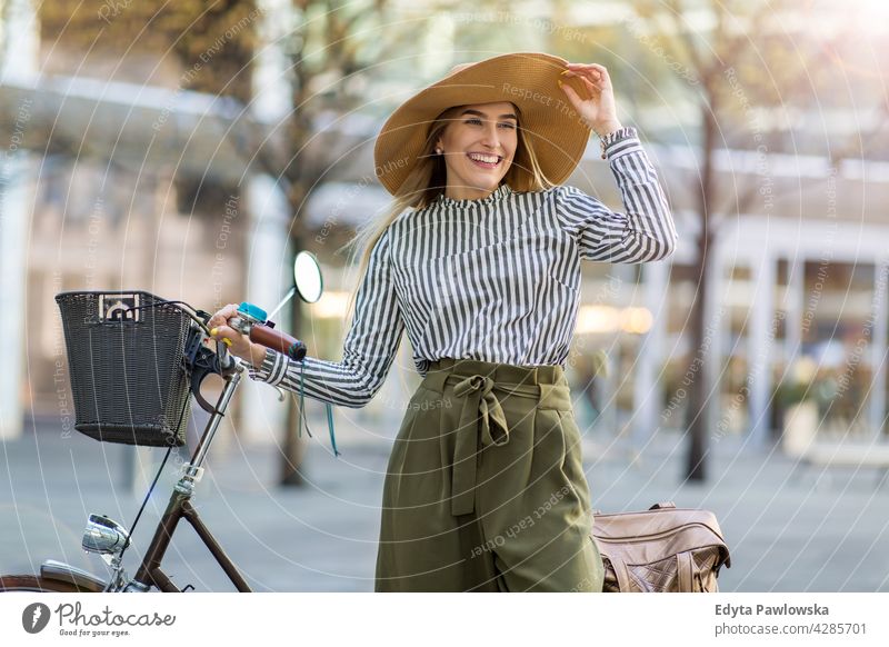 Young woman standing with her bicycle in the city straw hat holiday vacation fashion park green trees nature freshness enjoying lifestyle young adult people