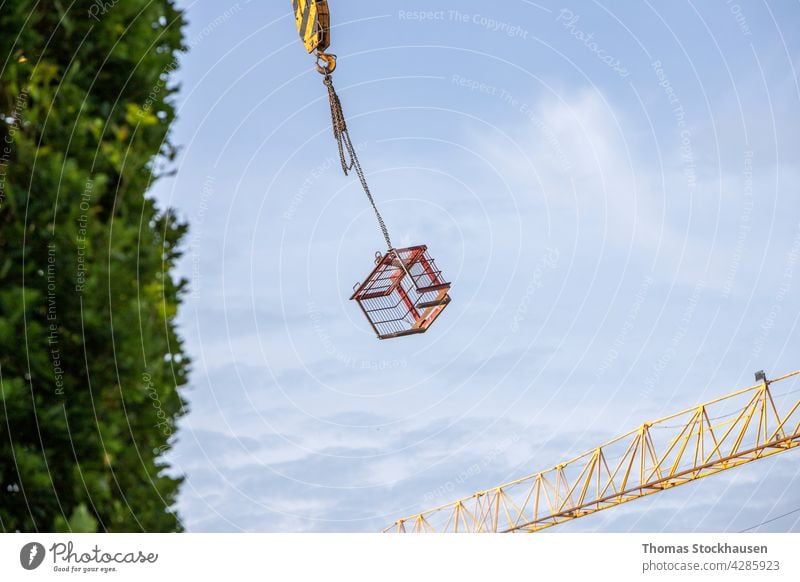 metal lattice box swinging on a construction crane activity apartment architecture background blue building site built business danger development engineering