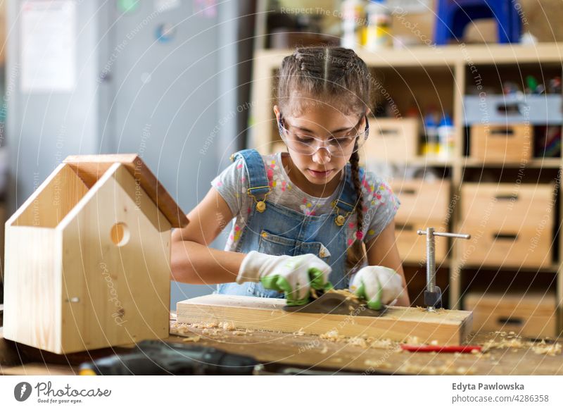 Girl building birdhouse in garage workshop working people child children kid kids girl girl power Skill craft Garage Hobby Lifestyle tools Concentration