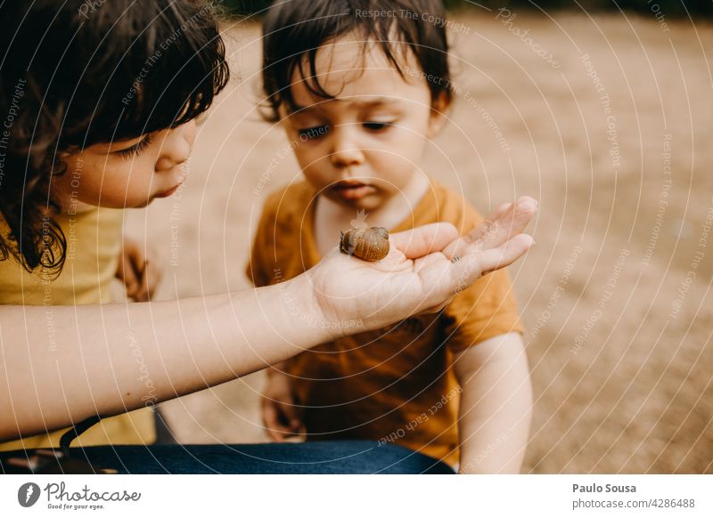 Brother and sister watching snail Snail Snail shell Mother Parenting Brothers and sisters Family & Relations Child childhood Curiosity Nature Lifestyle