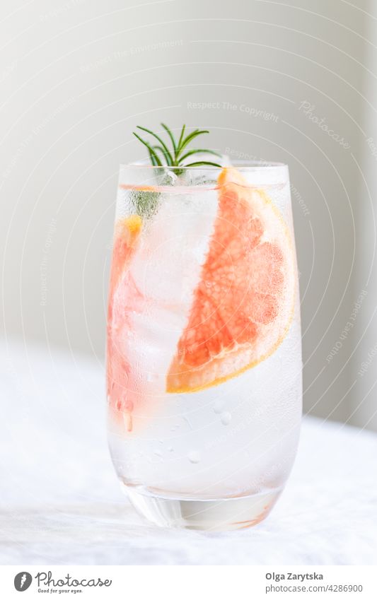 Cold water with grapefruit. drink cold lemonade ice rosemary summer glass refreshment citrus perspiration beverage white minimal cocktail background cool