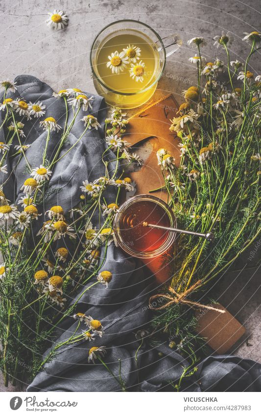 Herbal tea in glass cup with honey and  fresh medicinal plants. Dark concrete background with dark cloth. Top view. Natural health drinks concept herbal tea