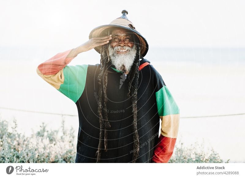 Serene hippie rastaman standing on field rastafarian african happy smile male delight cheerful culture ethnic reggae caribbean nature african american native