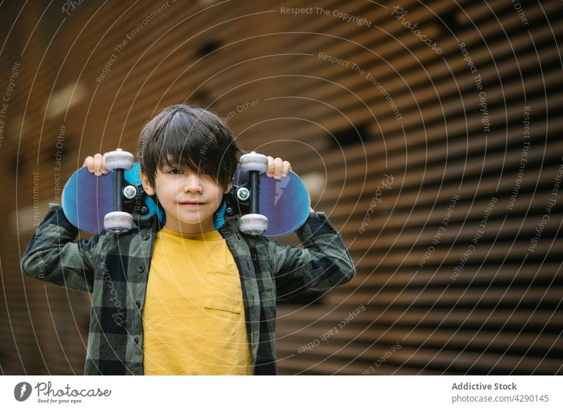 Positive boy with skateboard on street kid childhood hobby sporty skateboarder playful recreation carefree casual happy street style smile joy fun trendy cute