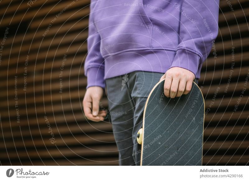 Anonymous skateboarder with skateboard on street boy teenage hobby sporty sidewalk street style pastime wall casual trendy cute walkway town pavement active