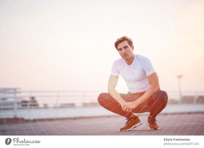 Young man doing exercise in urban area Jogger runner jogging running people young male energy clothing exercising fitness recreation sport healthy lifestyle